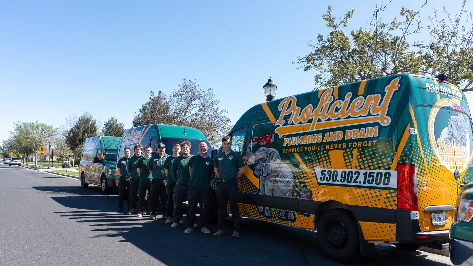 The Proficient Plumbing and Drain team standing beside a wrapped company van with the phone number visible on the livery