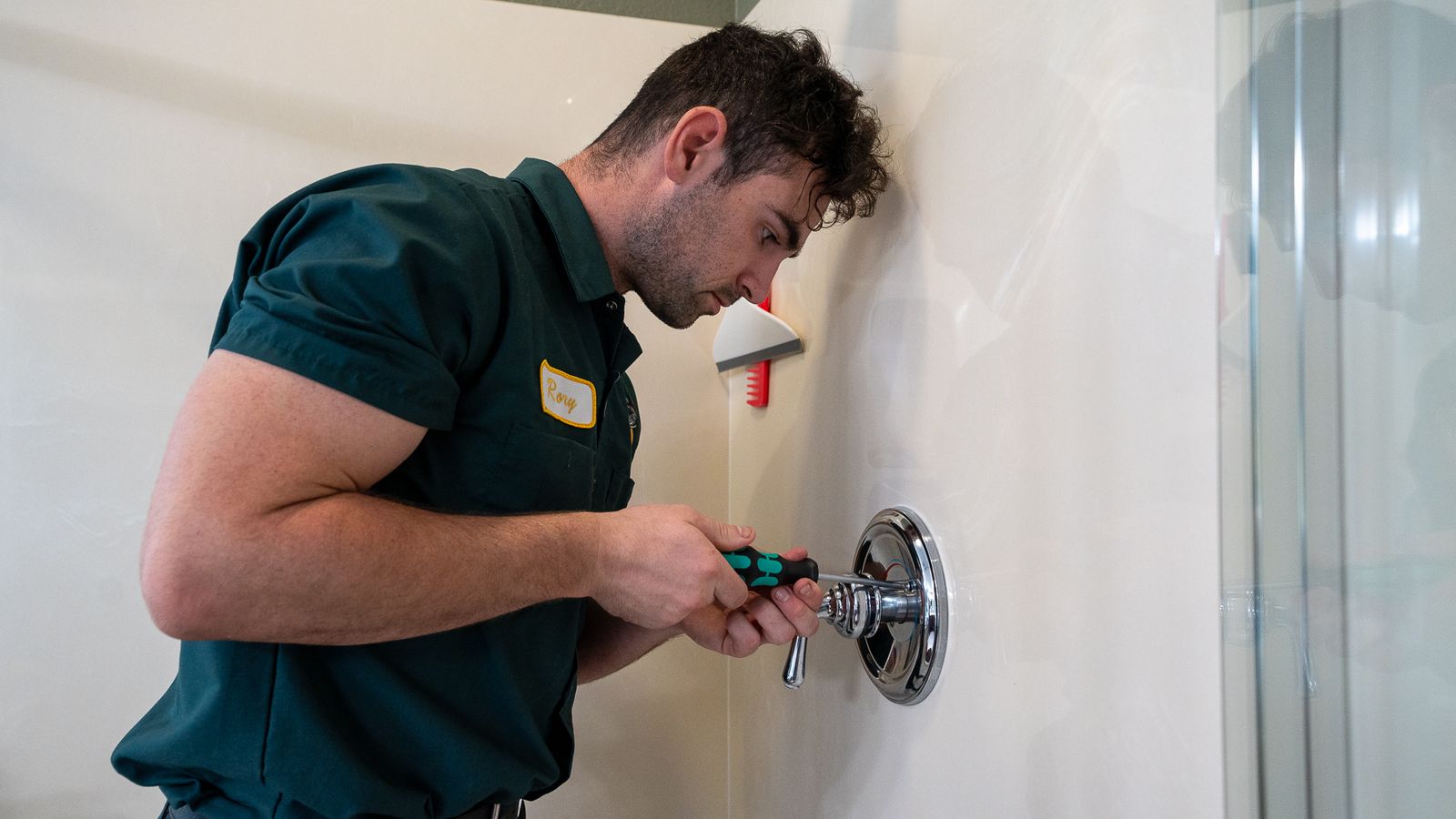 Proficient Plumbing technician removing the trim from a shower valve with a screwdriver